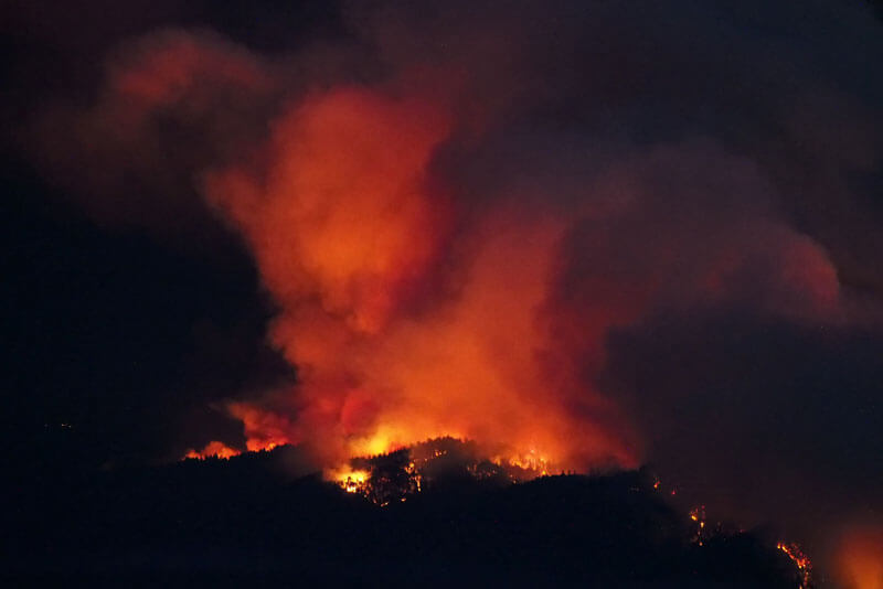 Flames cast an orange glow on massive plumes of smoke as the CZ fire burns on Butano Ridge. by Inklein