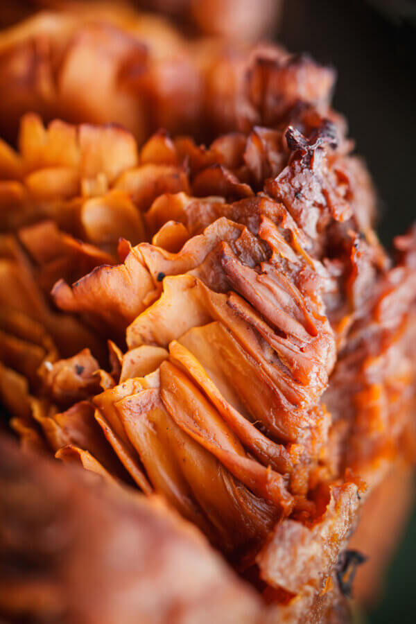 An up close photo of the frilly gills under the large orange mushroom’s cap range in color from a yellowish orange to reddish brown tipped with black as they decay, by Orenda Randuch